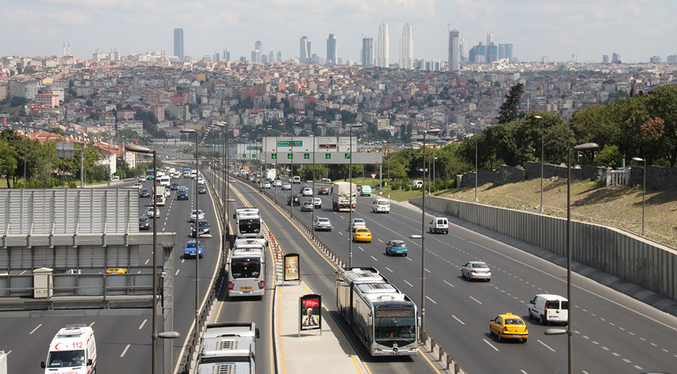 Diverse corsie autostradali trafficate con diversi autobus in un'unica corsia nel mezzo, di fronte allo skyline di Istanbul
