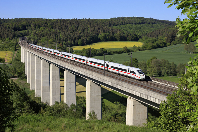 Un treno ICE bianco attraversa un ponte davanti a un paesaggio verde