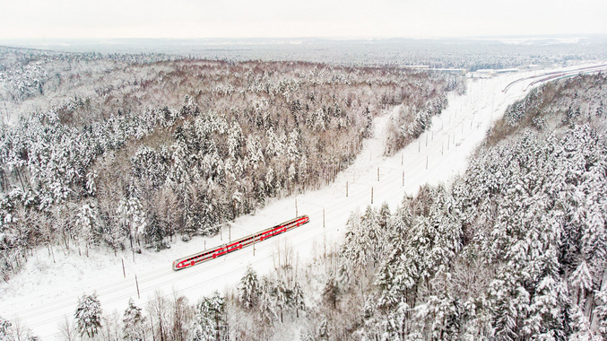 Litauische Eisenbahn LTG setzt auf IVU.rail Vista a volo d'uccello di un treno in una zona boschiva coperta di neve