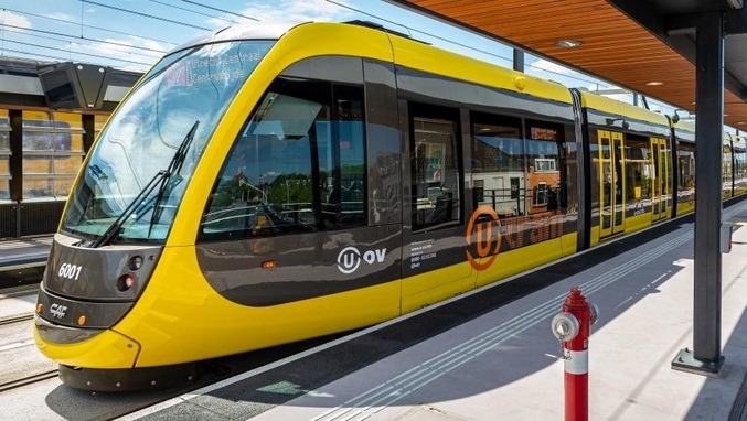 Un tram giallo e nero della provincia di Utrecht è fermo in una stazione.