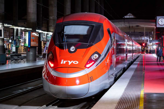 Una foto di un treno iryo rosso e argento visto di fronte, fermo al binario della stazione.