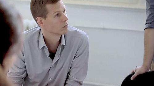 Mann im Gespräch mit seinen Kolleg:innen an einem Tisch