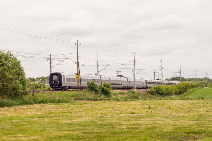 Un treno d'argento passa attraverso campi verdi