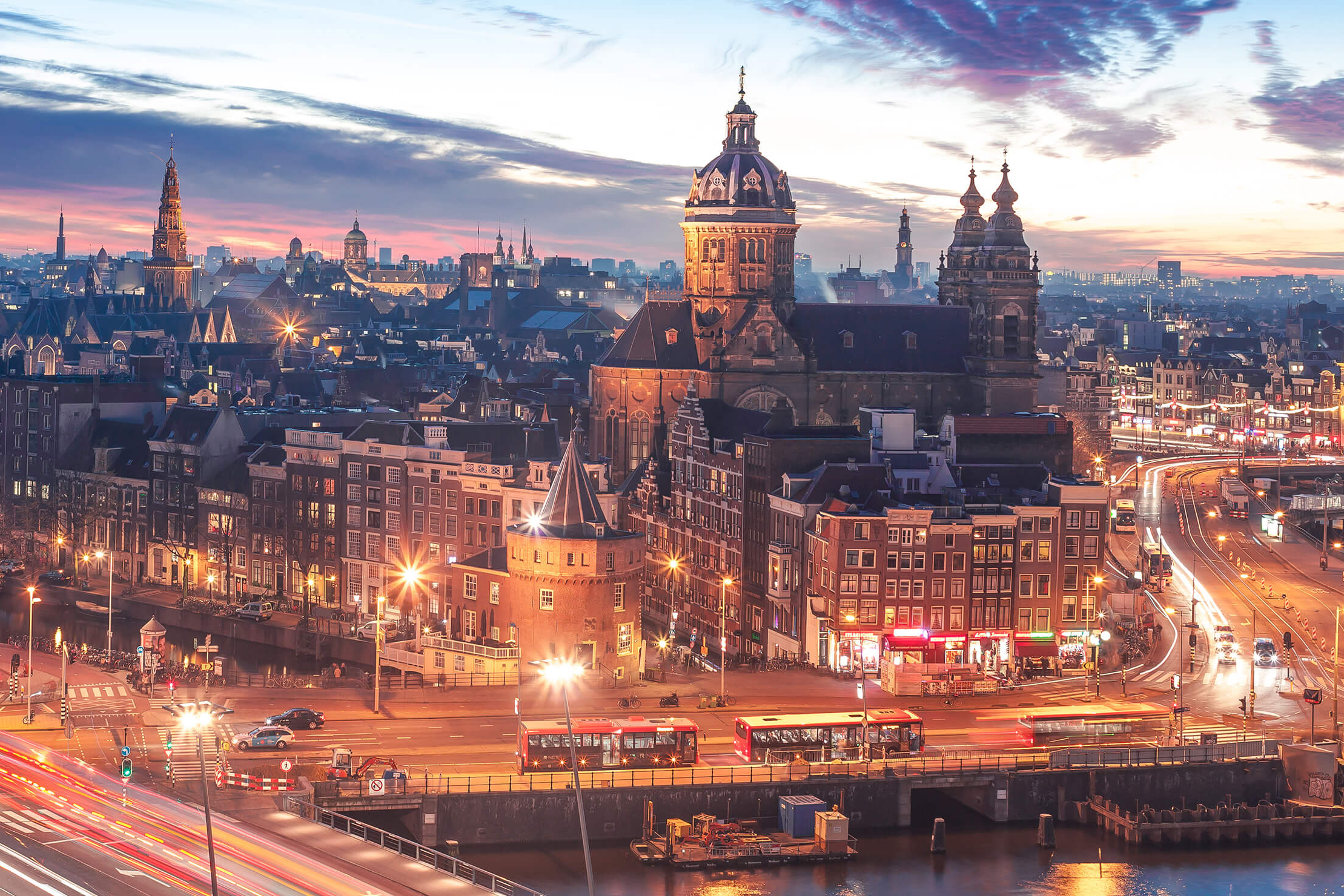 Skyline von Amsterdam in der Dämmerung mit hellen Lichtern