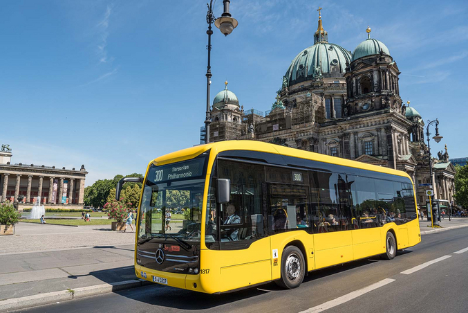 BVG_Elektrobus.jpg Autobus Mercedes Benz eCitaro giallo di fronte al Duomo di Berlino sotto un cielo blu.