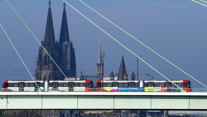 Il tram di Colonia corre su un ponte con la cattedrale di Colonia sullo sfondo.