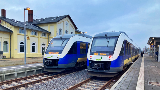 Due treni blu e bianchi di partenza si fermano in una stazione.