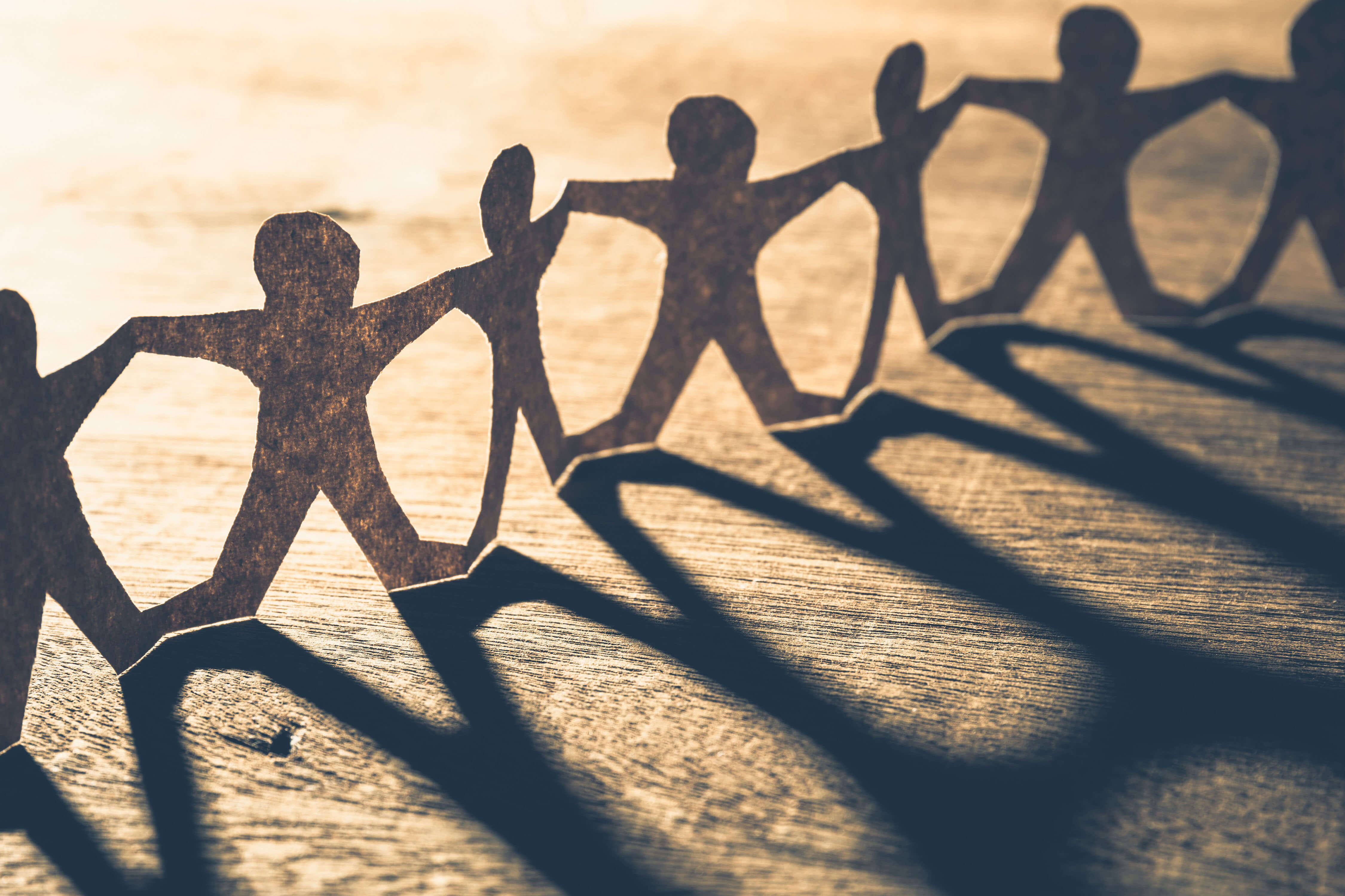 Figure umane ritagliate dalla carta in fila che si tengono per mano